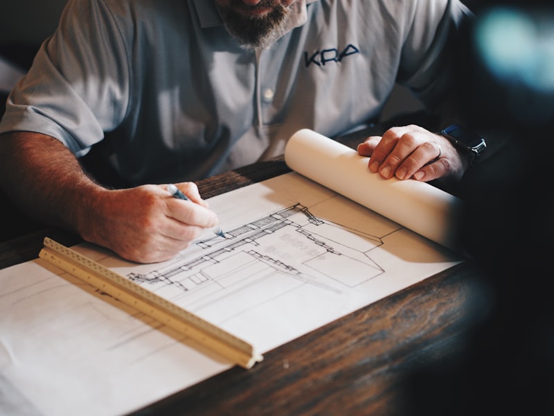 Hands drawing on a technical plan with a ruler