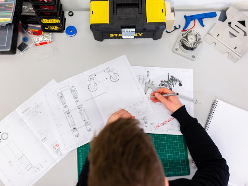 Technical drawings and tools spread across a workbench
